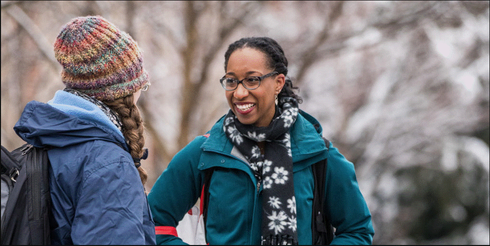 Female students laugh while walking to class as snow covers campus